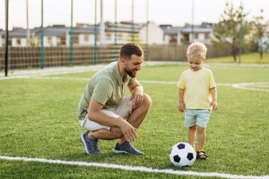 Baba oğul futbol sahasında oynuyorlar.