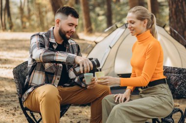 Ormanda çadırlarında çay içen bir çift.