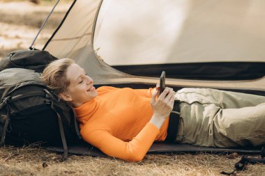 Ormanda çadırının yanında cep telefonu kullanan bir kadın gezgin.