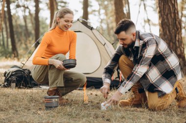 Ormanda birkaç gezgin suyu ısıtmak için gaz lambası kullanıyor.