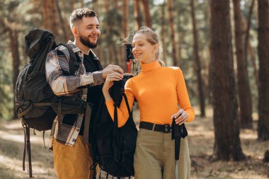 Çantalarla yürüyüş yapan ve ormanda yürüyen çiftler.