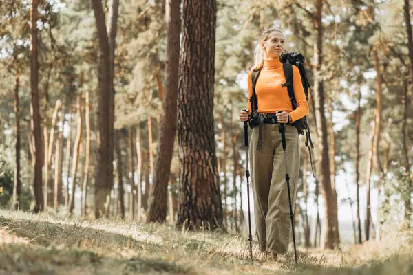 Woman hiking with walking sticks in forest