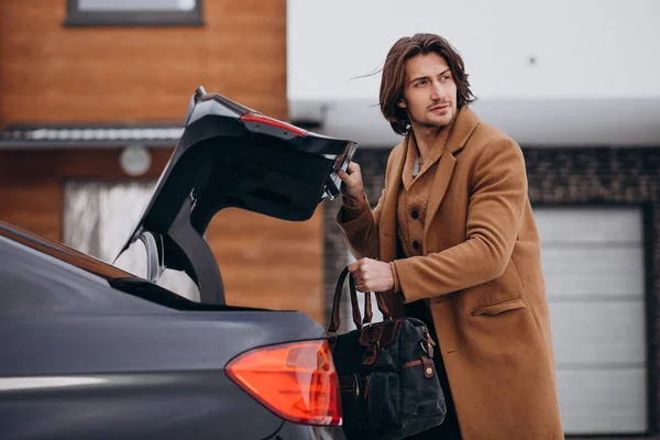 Young man packing his bag into a car