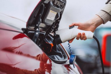 Elektrikli benzin istasyonunda kadın elektro arabayı şarj ediyor.