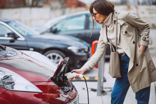 Woman charging electro car at the electric gas station