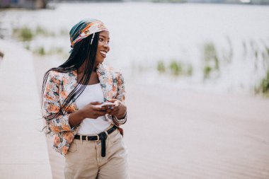 Parkta telefon kullanan Afrikalı Amerikalı bir adam.