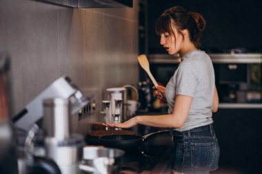 Sabahları mutfakta kahvaltı hazırlayan genç bir kadın.