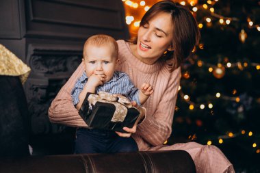 Anne ve küçük oğlu Noel ağacının yanında hediyelerini açıyor.