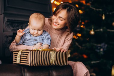 Anne ve küçük oğlu Noel ağacının yanında hediyelerini açıyor.