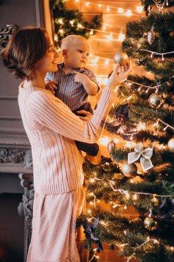 Anne ve küçük oğlu Noel ağacını oyuncaklarla süslüyorlar.