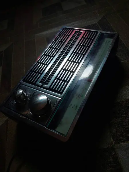 Radio receiver - box radio in black, retro technology. Radio on wooden floor.