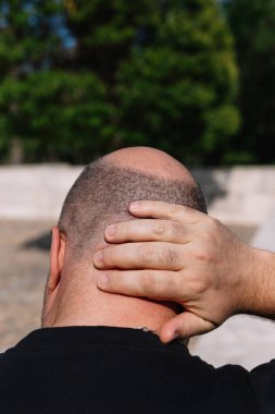 Saçları seyrelmiş ya da ensesinde tek eli olan bir erkek başının yakın plan görüntüsü.