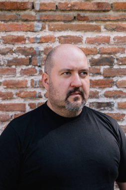 45 yaşında, kel, keçi sakallı ve bıyıklı bir adamın dış görüntüsü.