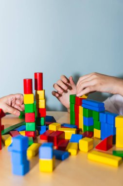 Terapide renkli tahta bloklarla çalışan ergen bir hastanın ve psikoterapistinin ellerine ön bakış. Terapi ve akıl sağlığı kavramı