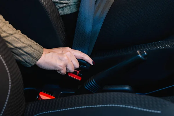 Close-up of female hand tightening seat belt inside her car. Road safety concept