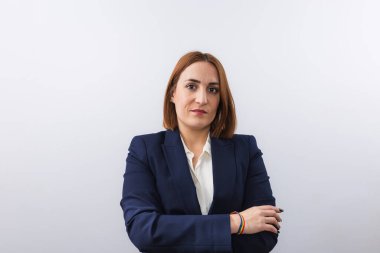 Genç, kızıl saçlı, ceket giymiş lezbiyen bir iş kadını portresi ve bileğinde gökkuşağı bileziği. Beyaz arkaplan ve kopyalama alanı. Eşitlik, haklar ve LGTBI gururu kavramı