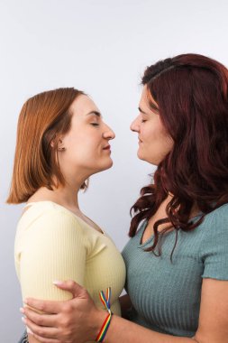 Birbirlerini öpmeden önce gözleri birbirine kenetlenmiş genç, kızıl saçlı lezbiyen çiftin yakın plan görüntüsü. Beyaz arka plan. LGTBI gurur ve haklar kavramı