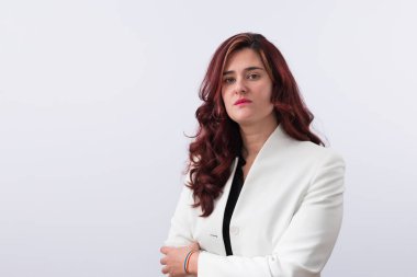 Genç, kızıl saçlı, ciddi tavırları olan lezbiyen bir iş kadınının yatay portresi. Beyaz ceket giymiş ve bileğinde gökkuşağı bileziği var. Eşitlik, haklar ve LGTBI gururu kavramı