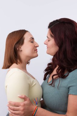 Birbirlerini öpmeden önce gözleri birbirine kenetlenmiş genç, kızıl saçlı lezbiyen çiftin yakın plan görüntüsü. Beyaz arka plan. LGTBI gurur ve haklar kavramı