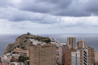 Yüksek açılı bir tepe manzarası ve Benidorm, İspanya 'da arka planda deniz olan binalar, çok bulutlu bir yaz günü, kara bulutlu bulutlar. Turizm ve inşaat kavramı