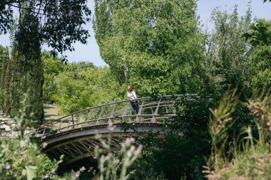 Olgun 45 yaşında bir kadın, güneşli bir günde, gözleri kapalı bir köprüde durup güneşli bir günde rahatça güneşlenir. Uzayı kopyala Sağlıklı yaşam tarzı kavramı