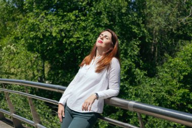 Olgun, 45 yaşında, gözleri kapalı güneşli bir günde yüzü güneşte dinlenen ve dinlenen bir kadın. Uzayı kopyala Sağlıklı yaşam tarzı kavramı