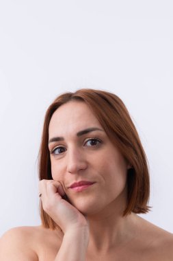 30 'lu yaşlardaki güzel bir kadının portresi. Kısa kızıl saçlı. Elinde yüzüyle kameraya bakıyor. Beyaz arka plan. Uzayı kopyala Doğal güzellik konsepti