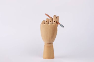 Tahta el, parmaklarıyla kalem tutuyor. Beyaz arka planda izole edilmiş. Uzayı kopyala Yazı, çizim, fikir ve yaratıcılık kavramı