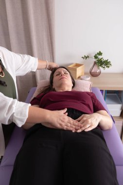 Terapistinin yanında acı ifadesi olan sedyede oturan olgun bir kadın. Terapi, sağlık, psikoterapi, kinezoloji ve akapi kavramı