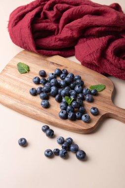 Tahtada taze yaban mersini, nane yaprakları ve bej arka planda kırmızı kumaş. Doğal ve kırsal tarzda. Sağlıklı beslenme, tazelik ve ev yemeği kavramı