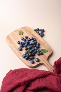 Kırsal ahşap tahtada yaban mersinli, naneli ve kırmızı kumaşlı minimalist bir hayat. Yumuşak ve uyumlu bir arka plan. Uzayı kopyala Sağlıklı beslenme, tazelik ve doğal ürünler kavramı