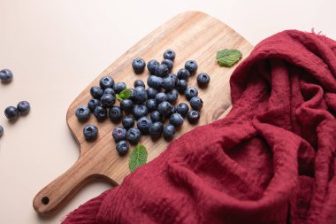 Bej arka planda ahşap tahta ve naneli yaban mersini. Kırmızı kumaş doku ekler. Beslenme, tazelik ve sağlıklı yemek kavramı