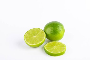 Tam kireç, yarım limon ve yeşil limon dilimi, beyaz arka planda izole edilmiş. Uzayı kopyala Meyve ve sağlıklı yeme konsepti