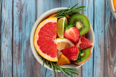 Üzerinde greyfurt, kivi, çilek, limon ve limon dilimleri olan bir kasenin üst görüntüsü. Canlı renkler ve doğal tazelik. Uzayı kopyala Sağlıklı beslenme konsepti ve vitaminler
