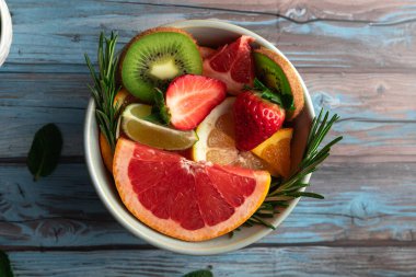 Çilek, greyfurt, kivi, kivi, kivi, kiraz ve turuncu renkli mavi kırsal arka plan ve parlak renkler. Uzayı kopyala Yaz kavramı, sağlık ve tazelik.