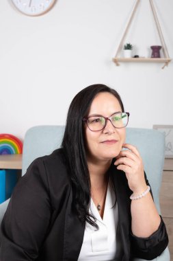 Çalışma odasında yaşlı bir kadın, gözlük takıyor ve zarif siyah beyaz kıyafetler giyiyor, düşünceli bir şekilde yan tarafa bakıyor. Uzayı kopyala Düşünce, karar verme ve mesleki deneyim kavramı