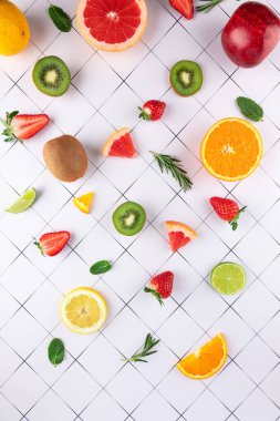 Beyaz geometrik arka planda taze meyvelerin üst görüntüsü. Çilek, narenciye ve kivinin yaratıcı düzenlemesi. Sağlıklı beslenme ve yaz kavramı