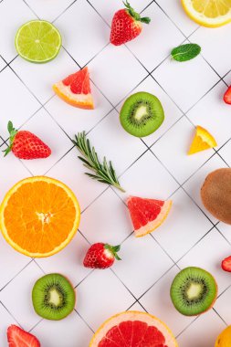 Portakal, kivi ve çilek gibi çeşitli meyvelerin beyaz geometrik arka planda düz bir kompozisyonda üst görünümü. Sağlıklı ve yaz mutfağı kavramı
