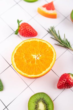 Yarım portakal, çilek, kivi ve biberiye yapraklı greyfurt dilimleri geometrik beyaz arka planda. Meyve ve sağlıklı yemek kavramı