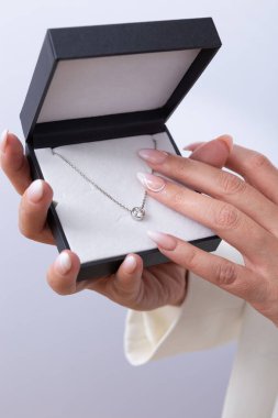 Elmas kolyeli siyah mücevher kutusu manikürlü tırnaklı kadın ellerinin elinde. Lüks kavramı, düğün, yıldönümü, değerli mücevher.