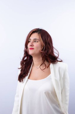 Kıvırcık saçlı, kırmızı dudaklı, sakin yüzlü, elmas kolye takan ve beyaz takım elbiseli bir kadının portresi. Uzayı kopyala Zarafet kavramı, doğal güzellik, zamansız tarz.