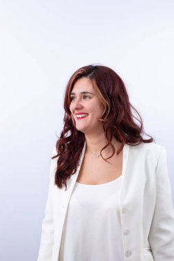 Kırmızımsı kıvırcık saçlı, parlak gülüşlü, kırmızı dudaklı, beyaz takım elbiseli ve elmas kolyeli 30 yaşında bir kadın. Uzayı kopyala Mutluluk, güven, zarafet ve başarı kavramı