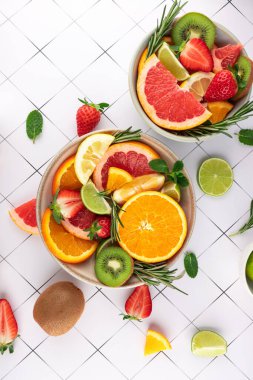 Çilekli taze meyve ve narenciye, kivi, portakal, greyfurt, limon, limon ve minimalist beyaz arka planda bitkiler. Yaz ve sağlıklı stil. Tazelik ve doğal yemek kavramı