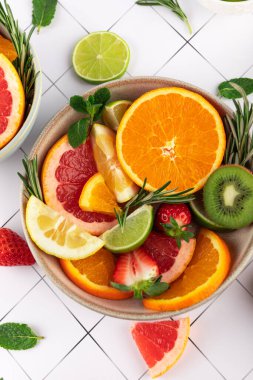 Beyaz arka planda taze narenciye, çilek, kivi ve otlarla dolu renkli bir hayat. Yaz ve sağlıklı stil. Sağlıklı beslenme kavramı