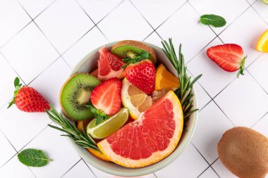 Bir kasedeki taze ve renkli meyvelerin üst görüntüsü: greyfurt, çilek, kivi, limon, limon ve turuncu üzerine siyah çizgiler. Uzayı kopyala Sağlıklı beslenme ve tazelik kavramı