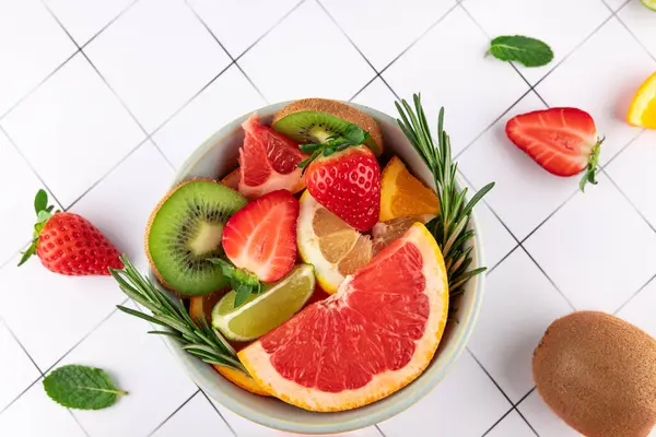 Bir kasedeki taze ve renkli meyvelerin üst görüntüsü: greyfurt, çilek, kivi, limon, limon ve turuncu üzerine siyah çizgiler. Uzayı kopyala Sağlıklı beslenme ve tazelik kavramı