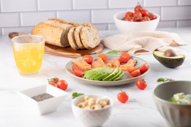 Parlak bir mutfakta çoklu tahıllı ekmek, avokado, somon ve domates ile sağlıklı besin bileşimi. Modern ve temiz stil. Doğal beslenme, yavaş yaşam tarzı