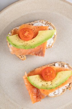 Somon, avokado ve çoklu tahıllı domatesli iki sağlıklı tost. Sağlıklı kahvaltı ve modern yaşam tarzı kavramı