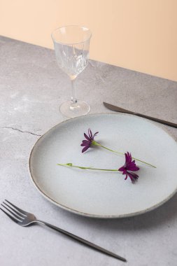 Çiçekli seramik tabak ve şeftali ve taş zemin üzerinde siyah çatal bıçak. Sahnede kristal cam var. Zarif basitlik ve modern tarz kavramı