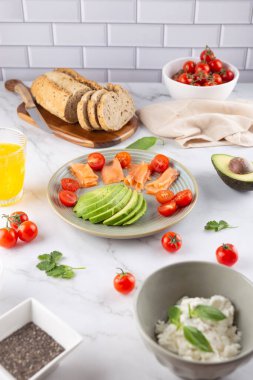 Avokado, somon, tam tahıllı ekmek ve kiraz domatesli hafif fayanslı kahvaltı. Dengeli beslenme. Doğal kahvaltı ve sağlıklı yaşam tarzı kavramı